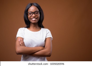 Studio Shot Of Young Beautiful African Zulu Woman Wearing White Shirt Against Brown Background