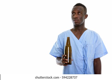 Studio Shot Of Young Black African Man Patient Thinking While Holding Bottle Of Beer Isolated Against White Background