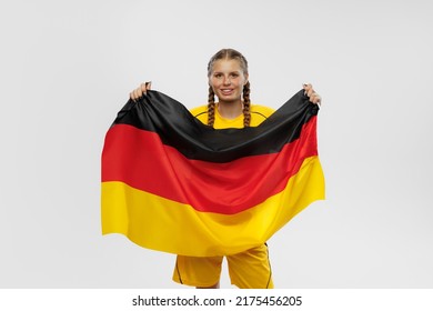 Studio shot of young emotional girl with german national flag supports favorite team isolated over white vackground. Soccer fans emotions, competition, sport, championship concept.