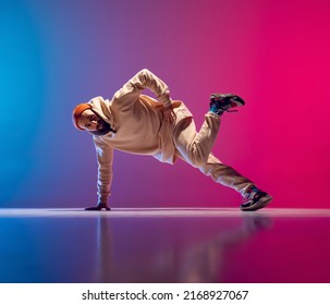 Studio shot of young flexible sportive man dancing breakdance in white outfit on gradient pink blue background. Concept of action, art, beauty, sport, youth. Dancer shows breakdance figures - Shutterstock ID 2168927067
