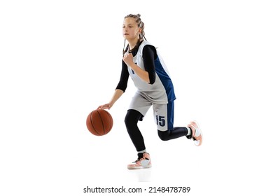 Studio Shot Of Young Girl, Basketball Player In Blue Uniform Training Isolated Over White Background. Dribbling Ball Before Throwing. Concept Of Sport, Active Lifestyle, Health, Team Game And Ad