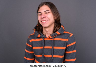 Studio shot of young handsome androgynous man with long hair against gray background - Powered by Shutterstock