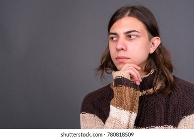 Studio shot of young handsome androgynous man with long hair against gray background - Powered by Shutterstock