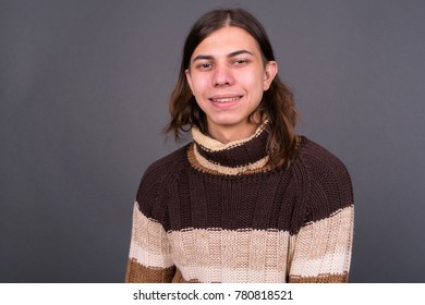 Studio shot of young handsome androgynous man with long hair against gray background - Powered by Shutterstock