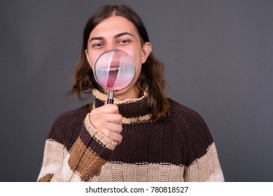 Studio shot of young handsome androgynous man with long hair against gray background - Powered by Shutterstock