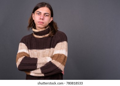 Studio shot of young handsome androgynous man with long hair against gray background - Powered by Shutterstock