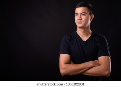 Studio Shot Of Young Handsome Asian Man Against Black Background