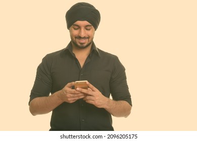 Studio shot of young handsome bearded Indian Sikh businessman isolated against white background
