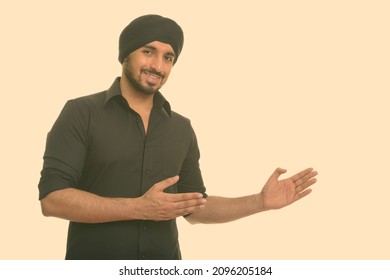 Studio shot of young handsome bearded Indian Sikh businessman isolated against white background