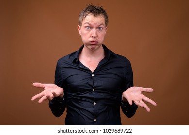 Studio Shot Of Young Handsome Man In Wet Clothes Against Brown Background