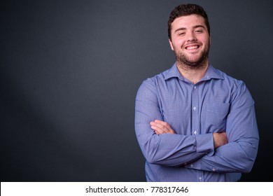 Studio shot of young handsome overweight businessman against gray background