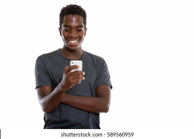 Studio Shot Of Young Happy Black African Teenage Boy Smiling While Using Mobile Phone