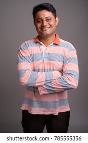 Studio Shot Of Young Indian Man Wearing Long Sleeve Striped Polo Shirt Against Gray Background