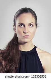 Studio shot of a young woman / girl thinking with gray background.