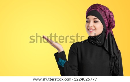 studio shot of young woman wearing traditional arabic clothing. she's holding her hand to the side