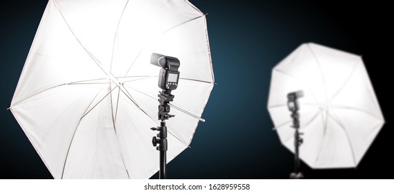 Studio speedlight flash and white umbrella reflector, equipment in a photo studio.