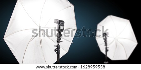 Studio speedlight flash and white umbrella reflector, equipment in a photo studio.