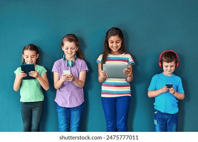 Studio, technology and group of kids for elearning, education and online research with smile. Happy students, girls and boy with digital app of tablet, smartphone and headphone by blue background