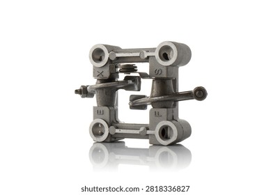 Studio three quarter perspective view of aluminum cylinder head rocker arm holder assembly featuring intake and exhaust valve rockers with adjustment screws, shaft springs, and cast bracket, shot on reflective white background showcasing four stroke engine valvetrain hardware.
