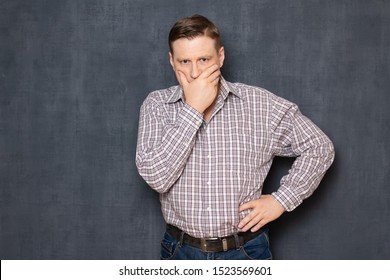 Studio waist-up portrait of upset unhappy focused man wearing shirt, covering mouth with hand to prevent crying, suffering while thinking about family tragedy or business failure, over gray background - Shutterstock ID 1523569601