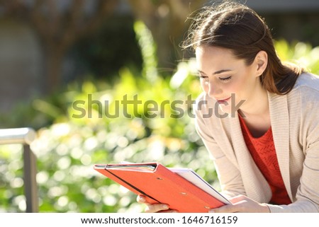Studious student reading notes studying sitting in a park or university campus