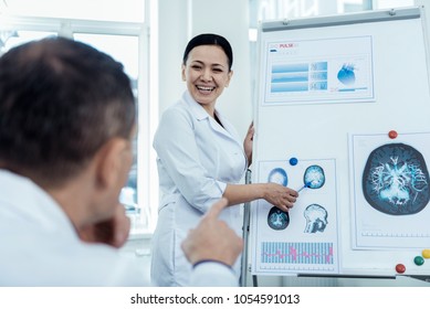 Study Brain Waves. Cheerful Asian Woman Presenting Her Research On Neurology To Her Colleague