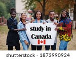 Study in Canada. Group of five african college students on campus at university yard hold white blank. Abroad countries for student concept.