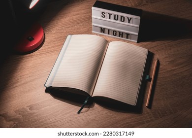 Study concept background. Notepad with blank pages and desk lamp on wooden table high angle view. Study time concept. Selective focus on notebook