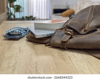 Study desk with a partially open backpack showing a laptop and a book, alongside a smartphone and a pencil case. Organized workspace scene with everyday school and office items, back to school concept