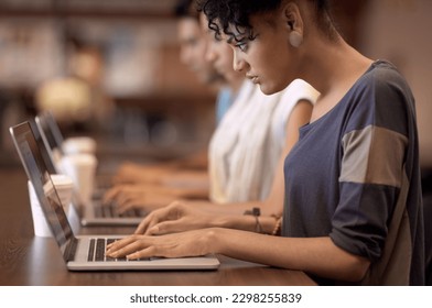 Study group dynamics. a studious young woman working on her laptop with blurred people in the background.