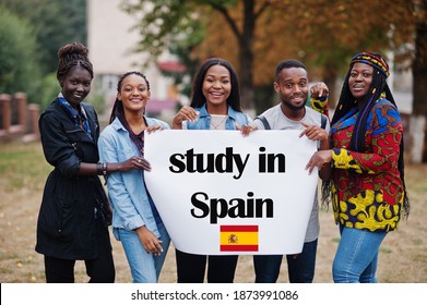 Study In Spain. Group Of Five African College Students On Campus At University Yard Hold White Blank. Abroad Countries For Student Concept.