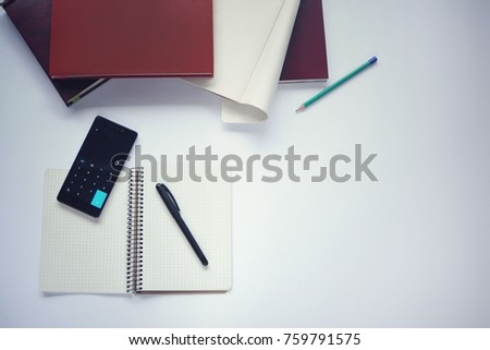 Study stuff. Education background. Aspects of education. Marker, paper, pencil, notebook, books, scissors and calculator application opened on mobile phone on the table.