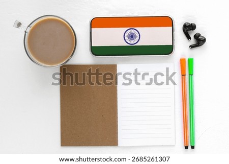Study workspace with notebook, pens, coffee, smartphone with indian flag on screen, concept of education, hindi language learning and culture