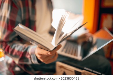 Studying, doing homework. One young caucasian man, student in glasses sitting with laptop at home or library background. Education, studying and student life concept.