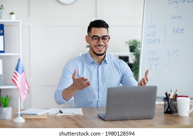 Studying English Online. Cheerful Arab Male Teacher Giving Foreign Language Lesson On Web Using Laptop. Young Tutor Explaining Grammar Rules To Students On Internet During Coronavirus Lockdown