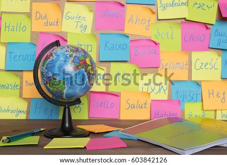 Studying languages concept, a globe and color notes with the word Hello in different languages.