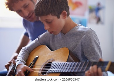 Studying the strings. Shot of a boy learning to play guitar from his father. - Powered by Shutterstock