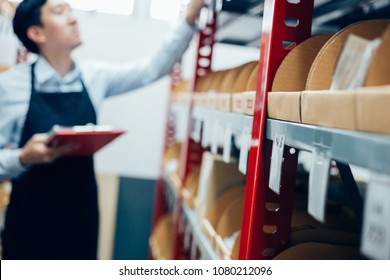 Stuff in stock in warehouse or storehouse checked and inspected by male inventory worker on duty - selective focus on cardboard in front - Powered by Shutterstock