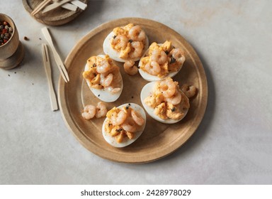 Stuffed boiled egg halves garnished with cooked shrimps and spices served as party appetizer- top view on plate - Powered by Shutterstock