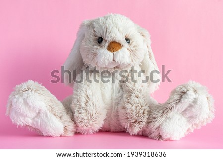 Stuffed bunny on pink background. Easter concept. Cute toy bunny sitting on colored background.