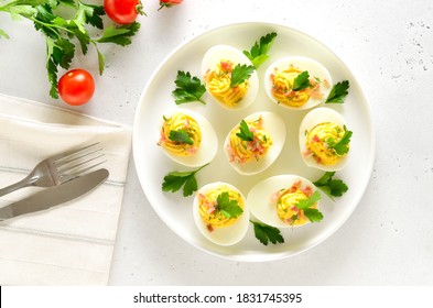 Stuffed eggs with egg yolk, bacon, mustard and parsley. Healthy diet food for breakfast. Top view, flat lay. - Powered by Shutterstock