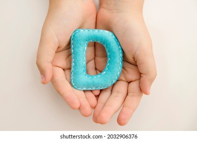 Stuffed Felt Letter Of The Alphabet In Open Hands Of Child. Kid Holding Handmade Capital Letter 