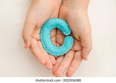 Stuffed Felt Letter Of The Alphabet In Open Hands Of Child. Kid Holding Handmade Capital Letter 