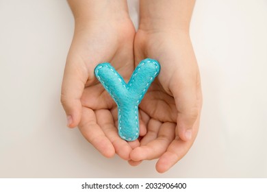 Stuffed Felt Letter Of The Alphabet In Open Hands Of Child. Kid Holding Handmade Capital Letter 