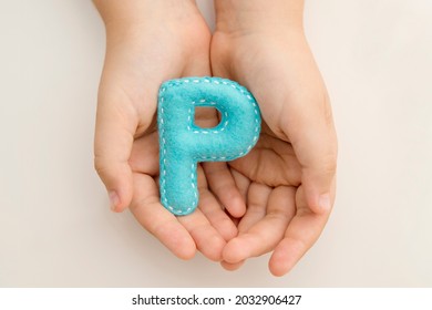 Stuffed Felt Letter Of The Alphabet In Open Hands Of Child. Kid Holding Handmade Capital Letter 