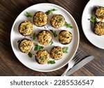 Stuffed mushrooms with cream cheese, bread crumbs and nuts on plate over wooden background. Top view, flat lay
