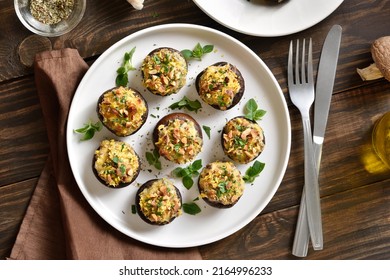 Stuffed mushrooms with cream cheese, bread crumbs and nuts on plate over wooden background. Top view, flat lay