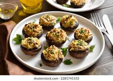 Stuffed mushrooms with cream cheese, bread crumbs and nuts on plate over wooden background. Close up view