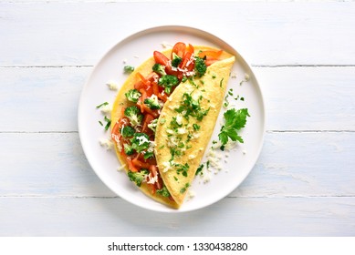 Фаршированный омлет с помидорами, красным болгарским перцем и брокколи на светлом деревянном фоне с копировальным пространством. Здоровое диетическое питание на завтрак. Вкусная утренняя еда. Вид сверху, плоская планировка.