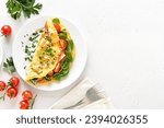 Stuffed omelette with tomatoes and spinach on light background with copy space. Top view, flat lay